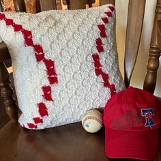 a baseball hat and pillow on top of a wooden chair next to a red ball