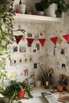 a desk with plants and pictures on the wall