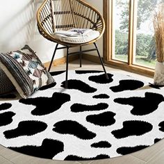 a black and white cow print rug in front of a window with a chair next to it