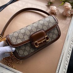 a woman's hand holding a brown and white purse on top of a table