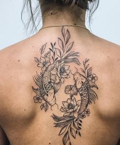 the back of a woman's neck with fish and flowers on it