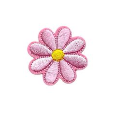 a pink flower with yellow center sitting on top of a white surface, in the shape of a daisy