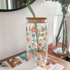 a glass vase with a flower design on it sitting on a table next to a mirror