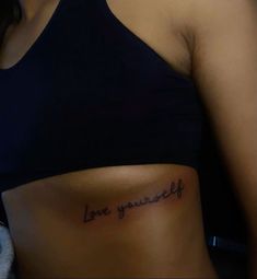 a woman's stomach with the words love yourself tattooed on it