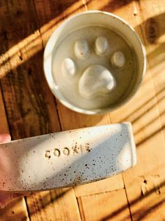 a person holding a spoon in front of a bowl on a wooden table with the word cook written on it