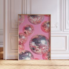 a pink wall with mirrored disco balls on it and a wooden floor in front of it