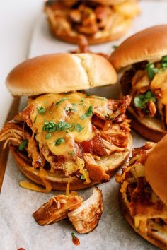 three pulled pork sandwiches with cheese on them