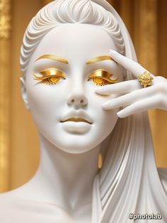 a white statue with gold eyeliners and a ring on it's finger