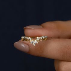 a woman's hand holding a gold ring with three small diamonds on the band