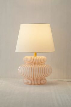 an orange and white lamp sitting on top of a table next to a white wall