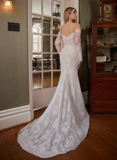 a woman in a white wedding dress is standing near a door and looking at something