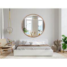 a white bed sitting under a round mirror in a bedroom next to a chair and potted plant