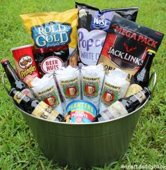 a bucket full of beer and snacks sitting in the grass