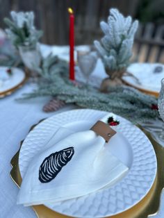 a white plate topped with a napkin next to a christmas tree and candlesticks