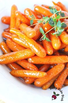 some carrots are on a white plate with green sprigs in the middle