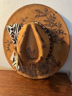 These custom hand burned wide brim western hats features a fabric hand tied band, and feathers. Every hat is customizable free of charge so please reach out to me via message so we can get a beautiful hat made for you. THE HAT PICTURED IS SOLD BUT I CAN MAKE ONE FOR YOU JUST LIKE IT. All designs are on the top of the hat unless otherwise asked. The band color is also customizable, so if you would like a specific color please let me know.  THE HAT LISTED IS CAMEL This hat is NOT a Charlie1Horse hat, and the price reflects that. The hat is 65% cotton 35% polyester. It is a vegan faux suede.  All hats are one size fits most with an adjuster tie on the inside. The hat is 22.8" or 57cm at its largest.  ALL HATS ARE MADE TO ORDER. NO HAT WILL BE 100% THE SAME DUE TO HAND BURNING EACH ONE INDIVID Hand Painted Western Hat Bands For Rodeo, Hand Painted Western Hat Bands For Festival, Western Hand Painted Hats For Country Events, Western Style Hand Painted Hat Bands For Country Events, Bohemian Wide Brim Hat Bands Hand Painted, Western Hand Painted Fedora For Country Events, Western Style Hand Painted Wide Brim Fedora, Western Style Wide Brim Hand Painted Fedora, Bohemian Hand Painted Fedora For Country Events