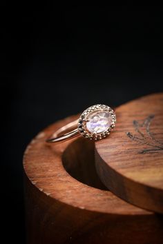 a close up of a ring on top of a wooden box with a black background