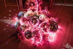 a bunch of disco balls sitting on top of a wooden floor covered in pink flowers