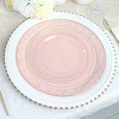 an empty plate on a table with pink and white plates, silverware and flowers