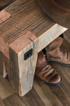 a pair of brown shoes sitting on top of a wooden bench next to a hat