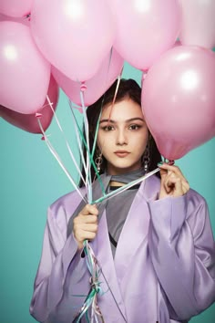 a woman holding pink balloons in front of her face