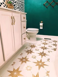 a bathroom with green walls and gold stars on the floor