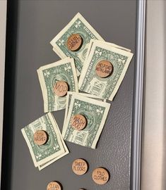 five different types of money sitting on top of a refrigerator freezer next to magnets