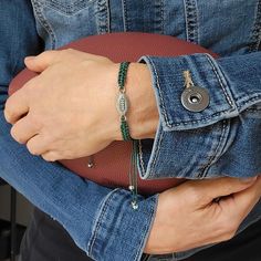 a person holding a football and wearing a green bracelet with a button on the end