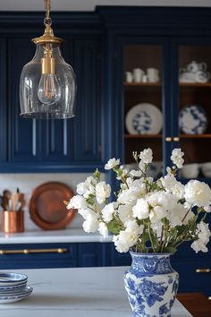 a blue and white vase filled with flowers on top of a kitchen counter next to plates