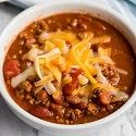 a white bowl filled with chili and cheese