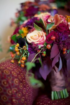 a bouquet of flowers sitting on top of a purple couch next to a red pillow