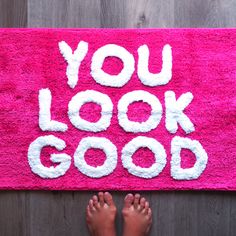 someone's feet on a pink rug that says you look good with white letters