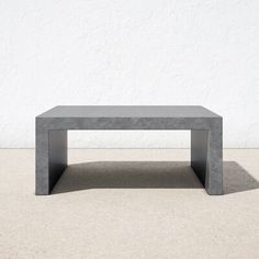 a concrete coffee table sitting in front of a white wall