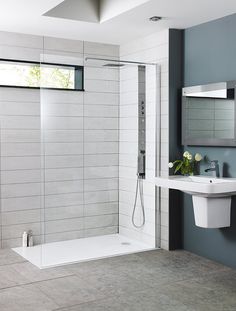 a bathroom with a walk in shower next to a white sink and mirror on the wall