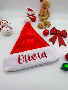 Santa Hat Christmas Hats Kids hat Personalized  Christmas Day Gifts for Boys and Girls Family Christmas Gift Merry Christmas hats  These personalized Christmas Santa hats are made with soft, plush red material and feature white faux fur trim. Each hat is customized with names, written in festive glittery red script, making them a perfect holiday accessory for family members or friends. The fluffy white pom-poms on top add a classic touch, while the personalized names--such as "Richard," "James," Richard James, Christmas Hats, Kids Hat, Christmas Gathering, Family Christmas Gifts, White Faux Fur, Christmas Hat, Christmas Day, Kids Hats