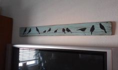 there are many birds sitting on the wall above the tv screen in this living room