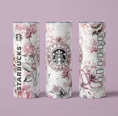 three starbucks coffee cups with floral designs on them, one is white and the other is pink