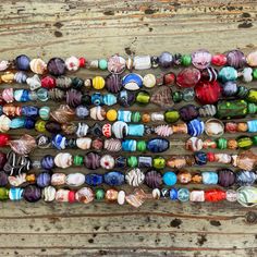 many different colored glass beads on a wooden surface