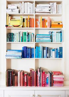 a bookshelf filled with lots of books on top of a white shelf next to a window