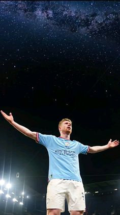 a man standing on top of a soccer field holding his arms out in the air