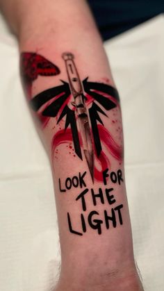 a person with a tattoo on their arm that reads look for the light and has a knife in it