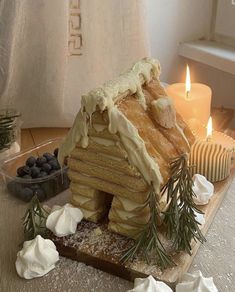 a cake shaped like a house sitting on top of a table next to some candles