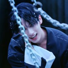 a man with black hair is holding onto chains