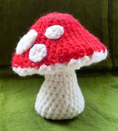 a red and white knitted mushroom sitting on top of a green couch