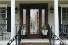 two potted plants sit on the front steps of a house with wrought iron railings