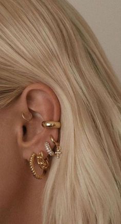 a woman with blonde hair wearing three different types of ear piercings