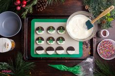 decorated cookies on a tray with icing and sprinkles next to christmas decorations