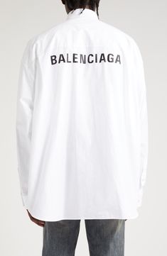 Balenciaga branding spans shoulder to shoulder beneath the back yoke of this button-down shirt cut in an oversized silhouette that befits the logo's length. 31" front length; 33" back length (size 2) Front button closure Button-down collar Long sleeves with button cuffs Chest patch pocket Curved hem 100% cotton Machine wash, line dry Imported Designer Clothing Classic Long Sleeve Tops With Logo, Classic Tops With Logo Print For Workwear, Summer Long Sleeve Shirt With Logo Print, Designer Oversized Tops For Spring, Balenciaga Branding, Titan Tattoo, Silk Shirt Men, Oversized Poplin Shirt, Balenciaga Shirt