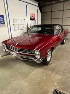 an old red car is parked in a garage