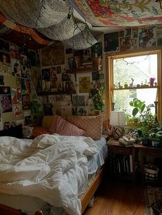 an unmade bed in a bedroom with many pictures on the wall and ceiling above it